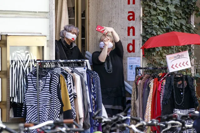 Women wearing masks take selfies outside a shop as businesses reopen following a shutdown in a measure to limit the spread of the virus in Graz, Austria on April 14, 2020. (Photo by Erwin Scheriau/APA/AFP Photo)