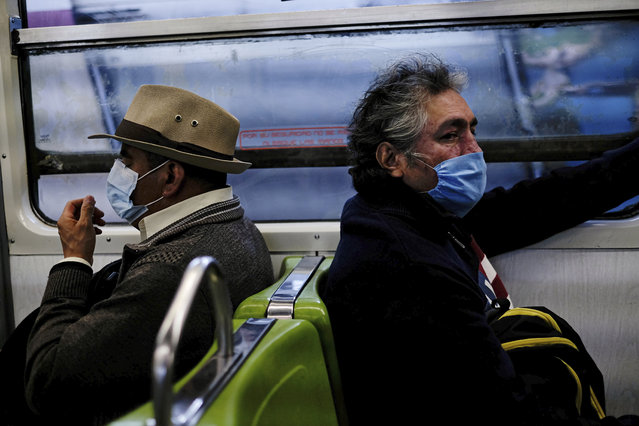 Commuters wear face masks, which were distributed by authorities at the Pantitlan metro station, in Mexico City, Friday, April 17, 2020. Authorities announced that starting Friday, it is mandatory to wear a mask when riding trains, to prevent the spread of the new coronavirus. (Photo by Fernando Llano/AP Photo)