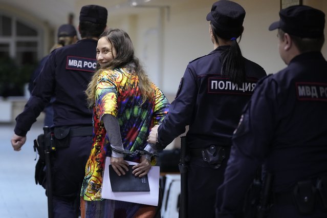 Sasha Skochilenko, a 33 year-old artist and musician, second left, is escorted by officers from the court room for a hearing in the Vasileostrovsky district court in St. Petersburg, Russia, Monday, November 13, 2023. A court in St Petersburg has to deliver a verdict to Skochilenko on charges of spreading “fakes” about the Russian military after she replaced four small price tags in a St. Petersburg supermarket with anti-war slogans. The prosecution asked to sentence her to 8 years in prison. (Photo by Dmitri Lovetsky/AP Photo)