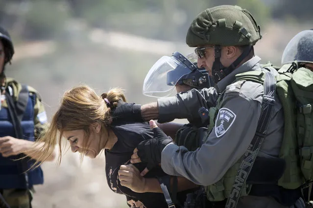 An Israeli border police officer detains a Palestinian woman during a protest against the expansion of the nearby Jewish settlement of Halamish, in the West Bank village of Nabi Saleh near Ramallah, Friday, September 4, 2015. (Photo by Majdi Mohammed/AP Photo)