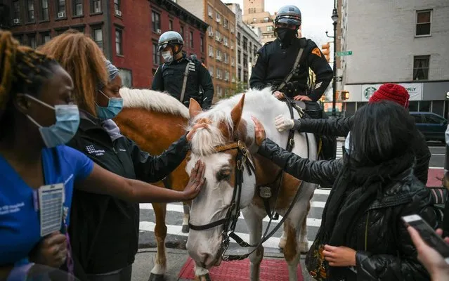 Nurses pet a police horse named Ralfie brought to cheer staffers at Lenox Hill Hospital in New York City on Saturday, April 18, 2020, as declining numbers of hospitalizations, intubations and deaths suggest the city is turning a corner in its fight against the coronavirus epidemic. (Photo by Miguel Juarez Lugo/ZUMA Wire/Rex Features/Shutterstock)