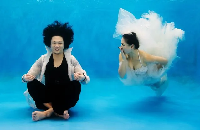 This photo taken on September 3, 2014 shows Qin Riyang (L) and Leng Yuting, both 26 years old, posing underwater for their wedding pictures at a photo studio in Shanghai, ahead of their wedding next year. Fiance Riyang said they had their wedding photographs taken underwater because “its romantic and beautiful”. Mr Wedding studio owner, Tina Lui, started providing underwater pictures four years ago. (Photo by Johannes Eisele/AFP Photo)