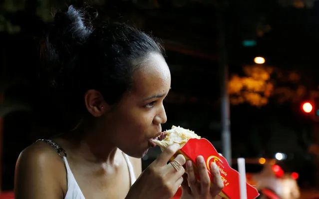 A woman eats a podrao, the Portuguese word for “rotten” (a hotdog or burger type sandwich assembled according to taste), in Rio de Janeiro, Brazil, April 8, 2016.. (Photo by Sergio Moraes/Reuters)