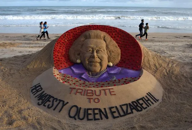 Children run past a sand sculpture depicting Britain's Queen Elizabeth, created by Indian sand artist Sudarsan Pattnaik and his students on a beach in Puri, Odisha, India on September 9, 2022. (Photo by Reuters/Stringer)