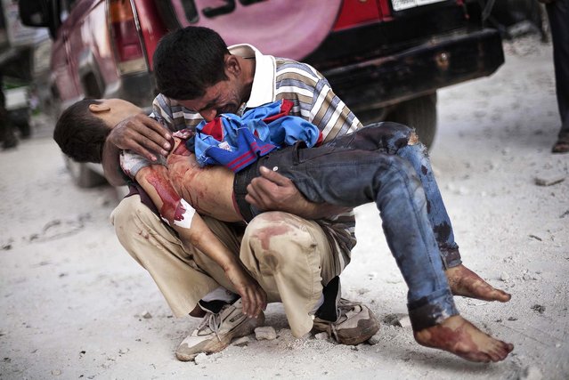 Aman cries while holding the body of his son, one of at least 34 people killed in the bombings, near Dar El Shifa hospital in Aleppo, Syria, on October 3, 2012. (Photo by Manu Brabo/Associated Press)