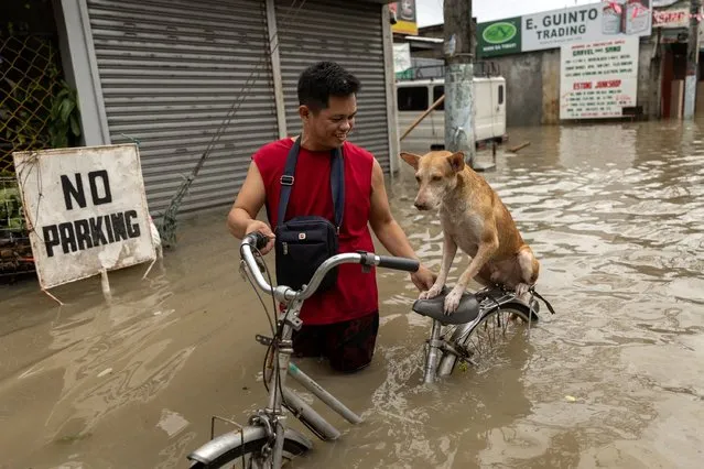 A-Jhay Celis, 35, wades through flood water with his dog Domeng, following heavy rains brought by tropical storm Nalgae, in Imus, Cavite province, Philippines on October 30, 2022. (Photo by Eloisa Lopez/Reuters)