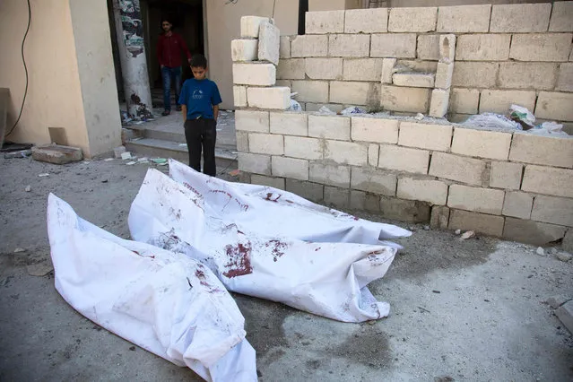 A child looks at bodies wrapped in plastic bags outside the Al-Bayan clinic following reported air strikes by government forces in the rebel-held Shaar neighbourhood of the northern city Aleppo on June 8, 2016. (Photo by Karam Al-Masri/AFP Photo)