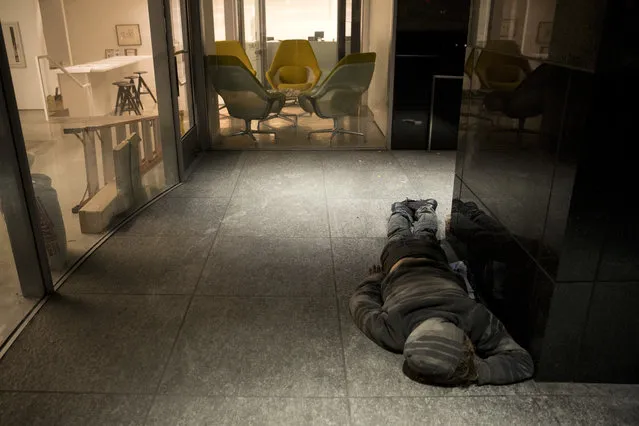 A homeless man sleeps on a concrete floor outside an office building under renovation Friday, December 1, 2017, in Los Angeles. (Photo by Jae C. Hong/AP Photo)