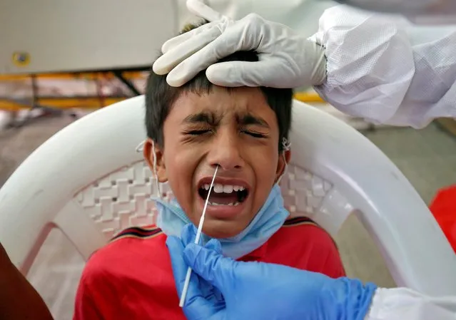 A boy reacts as a healthcare worker takes a swab from him for a rapid antigen test to tackle the coronavirus disease (COVID-19) outbreak, at a check-up point on a national highway in Ahmedabad, India, July 13, 2020. (Photo by Amit Dave/Reuters)