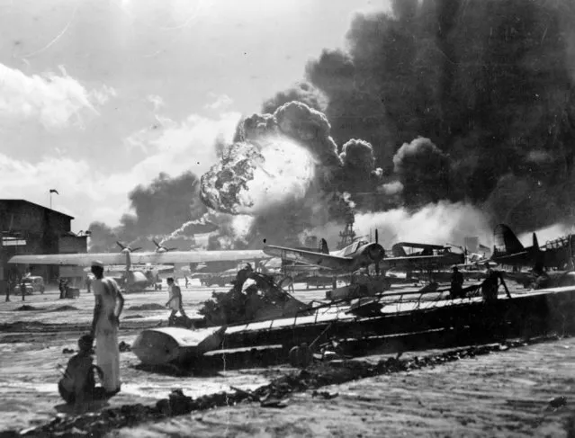 An explosion at the Naval Air Station, Ford Island, Pearl Harbour (Pearl Harbor) during the Japanese attack. Sailors stand amid wrecked watching as the USS Shaw explodes in the center background. The USS Nevada is also visible in the middle background, with her bow headed toward the left. (Photo by Fox Photos/Getty Images)