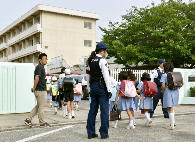 Police officers and teachers watch over students at an elementary school in the city of Okayama on Wednesday, June 1, 2016. (Photo by Kyodo News)