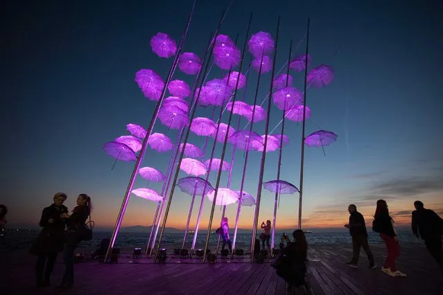 People stand around “Umbrellas”, the sculpture by Giorgos Zogolopoulos, as it is illuminated in pink light to mark the Breast Cancer Awareness Month in Thessaloniki in northern Greece October 21, 2014. (Photo by Alexandros Avramidis/Reuters)