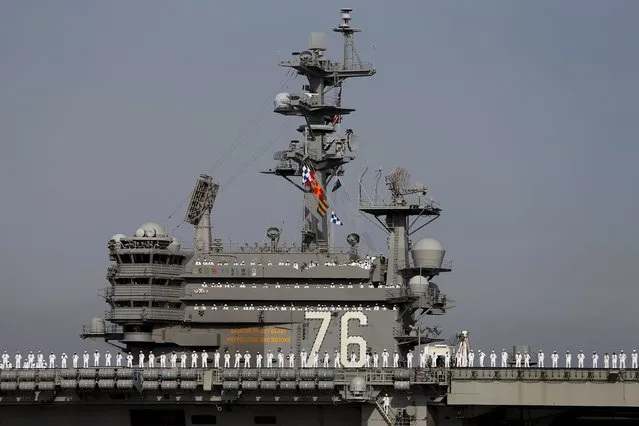 The crew members of the USS Ronald Reagan, a Nimitz-class nuclear-powered super carrier, stand at attention as it arrives at the U.S. naval base in Yokosuka, south of Tokyo, Japan, October 1, 2015. (Photo by Yuya Shino/Reuters)