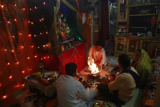 In this Tuesday, September 6, 2016 photo, Raju Laljibhai Dipikar, 50, second right, along with his wife Padma and Hindu priests offer prayers to an idol of elephant-headed Hindu god Ganesha at his home, on the second day of Ganesha Chaturthi festival in Mumbai, India. (Photo by Rafiq Maqbool/AP Photo)