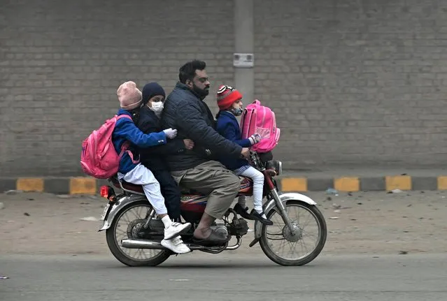 A man and children ride a motorcycle on their way to school after they were reopened in Lahore, Pakistan, 09 January 2023. Schools were reopened on 09 January after the winter vacations were extended for a week on direction of Lahore High Court due to bad air quality index. (Photo by Rahat Dar/EPA/EFE)