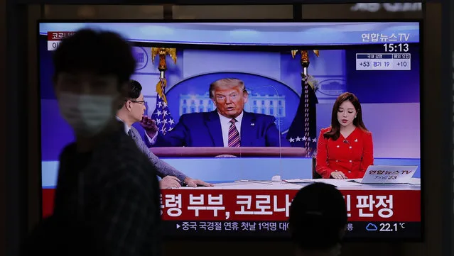 A man wearing a face mask walks near a TV screen reporting about U.S. President Donald Trump and first lady Melania Trump during a news program with a file image of Trump at the Seoul Railway Station in Seoul, South Korea, Friday, October 2, 2020. Trump said early Friday that he and Melania Trump have tested positive for the coronavirus, a stunning announcement that plunges the country deeper into uncertainty just a month before the presidential election. The Korean letters read: “President Donald Trump and first lady Melania Trump tested positive for COVID-19”. (Photo by Lee Jin-man/AP Photo)