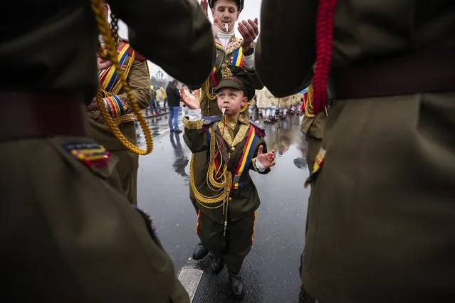 People wearing communist era military uniforms, decorated with colorful items, take part in a parade showcasing winter traditions from the northeast of the country in Bucharest, Romania, Sunday, December 18, 2022. (Photo by Andreea Alexandru/AP Photo)