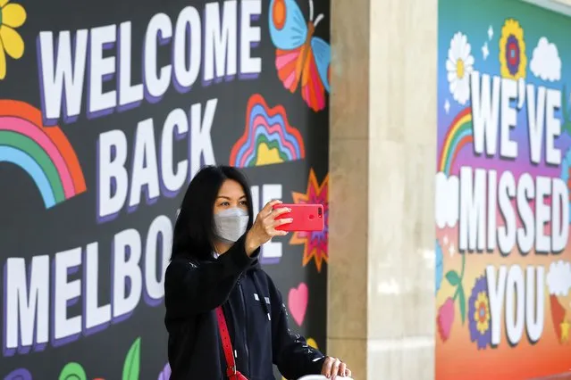A woman takes a selfie in front of signage in Melbourne, Australia, Wednesday, October 28, 2020. Australia’s second largest city of Melbourne which was a coronavirus hotspot emerges from a nearly four-months lockdown, with restaurants, cafes and bars opening and outdoor contact sports resuming on Wednesday. (Photo by Asanka Brendon Ratnayake/AP Photo)