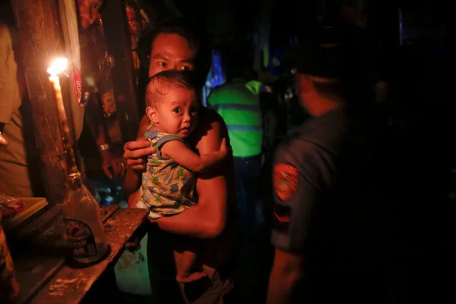 A man holds a baby as police searches a slum during a drug raid, in Manila, Philippines, October 7, 2016. (Photo by Damir Sagolj/Reuters)