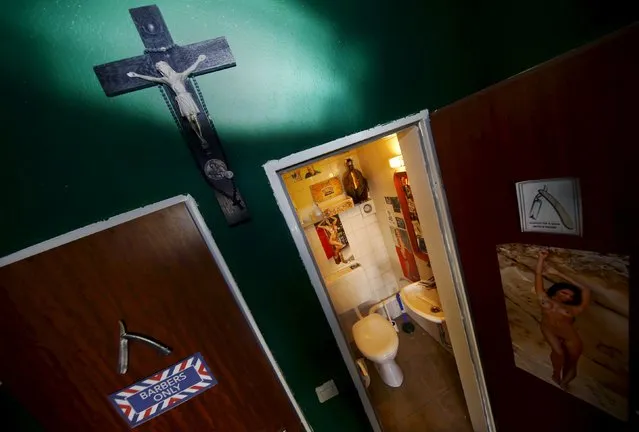 A cross hangs outside the toilet in Torreto Barbershop in Frankfurt, Germany, October 13, 2015. The toilet is used by the visitors and shop owner, Alex "Torreto" Velios who lives and works at his shop in Frankfurt. (Photo by Kai Pfaffenbach/Reuters)