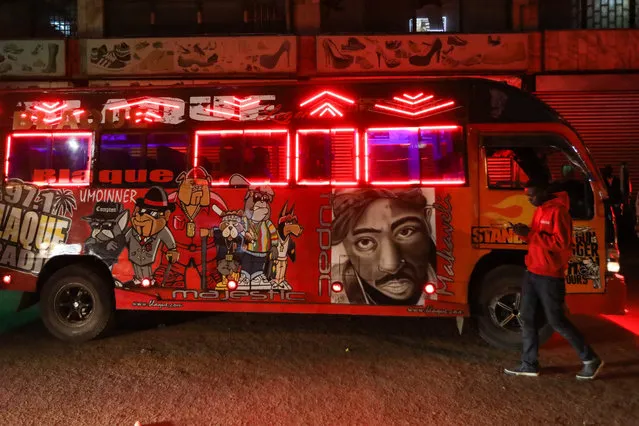 A man (R) walks next to a matatu painted with graffiti portraits of musicians as the crew wait for passengers at night in the streets of Nairobi, Kenya, 23 March 2018. (Photo by Daniel Irungu/EPA/EFE)