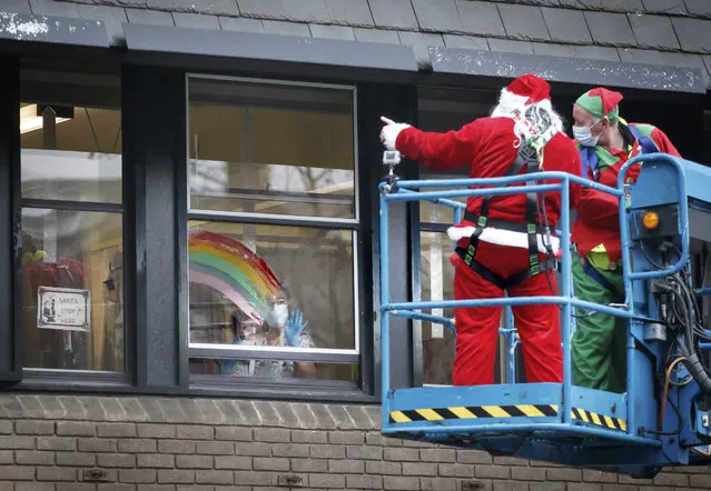 A man dressed as Santa Claus waves to patient Emma from a cherry picker outside Leeds Children's Hospital in Leeds, England, Monday December 21, 2020. “Operation Airborne Santa” transported Santa using the cherry picker to all four floors of the hospital to talk to patients from a safe distance, after visits to the wards were stopped to prevent the spread of the coronavirus among patients, their families and hospital staff. (Danny Lawson/PA Wire via AP Photo)