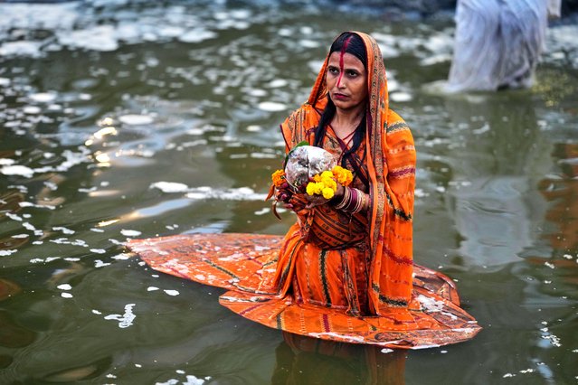 A devotee prays to the sun standing from the banks of the river Yamuna during the Chhath festival, which is celebrated for the well-being and prosperity of one's family, in New Delhi, India, Monday, October 27, 2025. (Photo by Manish Swarup/AP Photo)