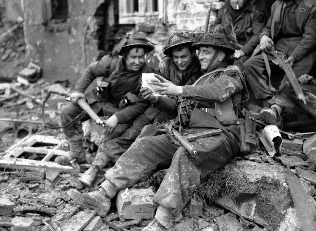 Happiness registers on the faces of these British soldiers as they read their first mail on German soil, amid the ruins of a German village, on the road to the Rhine on February 15, 1945. From left to right; Private J. Laird, from Scotland, Private J. Bryce, from Scotalnd and Corporal D. Devine from England. (Photo by AP Photo)