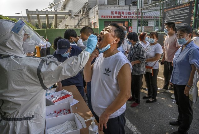 A Chinese epidemic control worker wears a protective suit and mask while performing a nucleic acid test for COVID-19 on a man who has had contact with the Xinfadi Wholesale Market or someone who has, at a testing center on June 16, 2020 in Beijing, China. Authorities are trying to contain the outbreak linked to the Xinfadi wholesale food market, Beijing's biggest supplier of produce and meat. Several neighborhoods have been locked down and at least two other food markets were closed, as tens of thousands of people are being urged to get tested for COVID-19 at sites set up around the city. The outbreak has triggered fears of a second wave of infection after 56 straight days with no domestically transmitted cases in the capital. More than 8,000 vendors and staff at Xinfadi have already been tested, according to city officials, who are using contact tracing to reach an estimated 200,000 people who have visited the market since May 30. (Photo by Kevin Frayer/Getty Images)