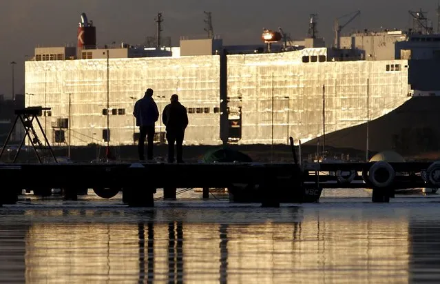 Two people are silhouetted against the hulk of a car carrier ship docked in Melbourne in this July 21, 2010 file photo. Australia is expected to release trade data this week. (Photo by Mick Tsikas/Reuters)