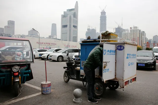 A man unloads parcels from a vehicle of the ZTO Express delivery service near the Central Business District in Beijing, China, October 27, 2016. (Photo by Thomas Peter/Reuters)