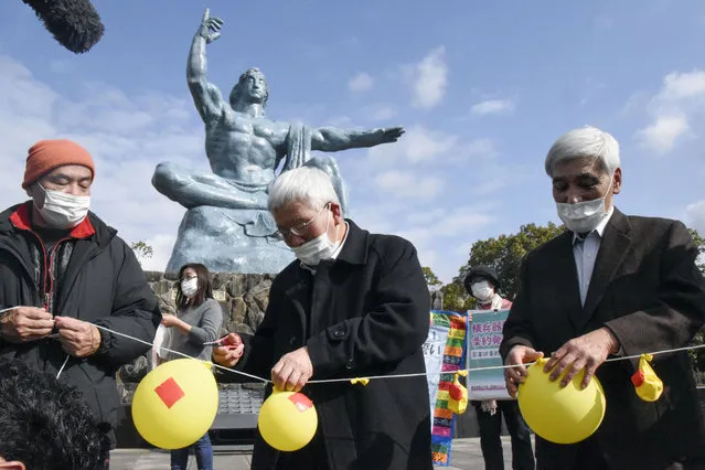 Participants deflate balloons in hope of neutralizing and demolishing nuclear warheads, during a memorial gathering at Peace Park in Nagasaki, southern Japan Friday, January 22, 2021. The first-ever treaty to ban nuclear weapons entered into force on Friday, hailed as a historic step to rid the world of its deadliest weapons but strongly opposed by the world's nuclear-armed nations. (Photo by Kyodo News via AP Photo)