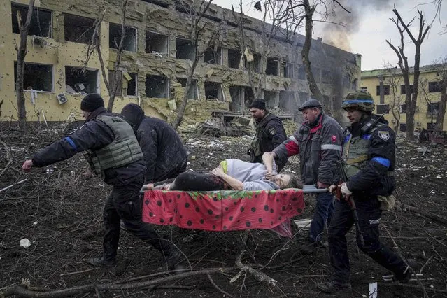 Ukrainian emergency employees and volunteers carry an injured pregnant woman from the damaged by shelling maternity hospital in Mariupol, Ukraine, Wednesday, March 9, 2022. (Photo by Evgeniy Maloletka/AP Photo)