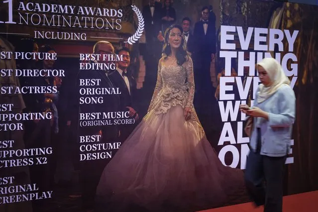 People walk next to giant posters of Michelle Yeoh during the 95th Academy Awards Live View event at a cinema in Kuala Lumpur, Malaysia, Monday, March 13, 2023. Michelle Yeoh was nominated for the Academy Award for best actress. (Photo by Vincent Thian/AP Photo)