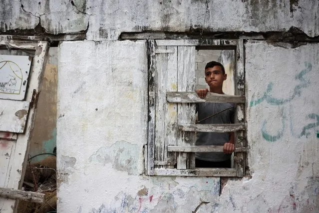 A Palestinian teenager takes shelter inside a ruined house during rain in Gaza City on June 13, 2023. (Photo by Mohammed Abed/AFP Photo)