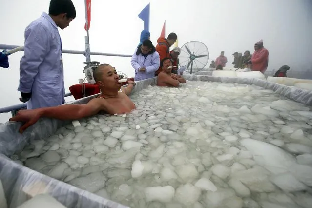 In this photo taken Sunday January 25, 2015, contestants with ice pop in their mouth dip in a pool of ice-water during the cold endurance challenge event on Zhangjiajie's Tianmen Mountain in central China's Hunan province. (Photo by AP Photo)