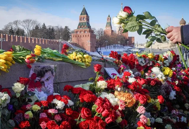 People place flowers at the site of the assassination of Russian opposition politician Boris Nemtsov while marking the 6th anniversary of Nemtsov's death, in central Moscow, Russia on February 27, 2021. (Photo by Tatyana Makeyeva/Reuters)