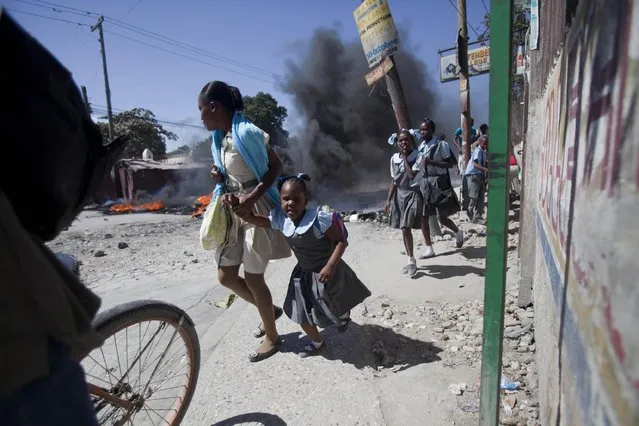 Students move past a burning barricade set by striking public transportation drivers at the start a their two day strike over the cost of fuel in Port-au-Prince, Haiti, Monday, February 2, 2015. Unions representing drivers say the government's cuts to the regulated cost of diesel and gasoline do not go far enough given the drop in global oil prices. (Photo by Dieu Nalio Chery/AP Photo)
