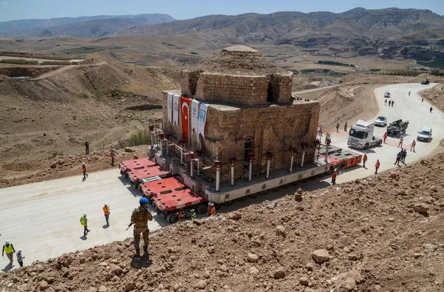 A Tukish soldier stands guard as the Artuklu Hamam, a centuries- old bath house weighing 1,600 tonnes, is loaded onto a wheeled platform an moved down a specially constructed road, on August 6, 2018, from the southeastern town of Hasankeyf to a new location to avoid being engulfed under floodwaters by a controversial dam project. (Photo by Ilyas Akengin/AFP Photo)