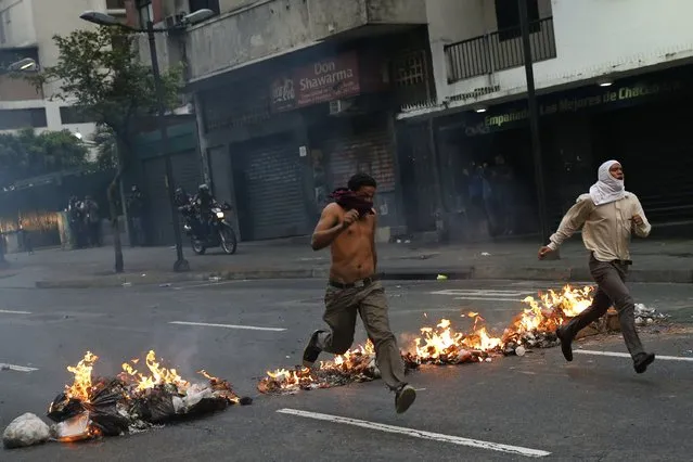 Opposition students run from police and past burning trash as they protest against President Nicolas Maduro's government in Caracas February 12, 2015. (Photo by Jorge Silva/Reuters)