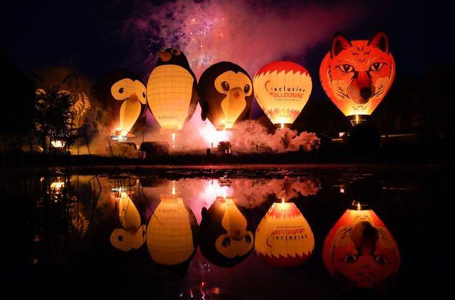 Balloons light up as they are tethered to the ground as they take part in the night glow during the Isle of Wight Balloon Festival at Robin Hill Country Park, Isle of Wight, England on Saturday, May 27, 2023. (Photo by Andrew Matthews/PA Images via Getty Images)
