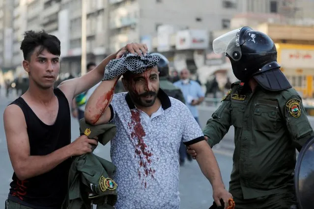 Members of Iraqi security forces escort an injured demonstrator during an anti-government protest in Baghdad, Iraq on May 25, 2021. (Photo by Khalid al-Mousily/Reuters)