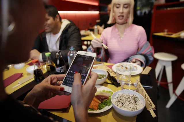 Customer fashion blogger Clizia Incorvaia, left, takes pictures of her dishes, as she has lunch with her friend singer Vittoria Hyde at the “This is not a Sushi bar” restaurant, in Milan, Italy, Tuesday, October 16, 2018. Although this is the sixth restaurant the brand “This is not a sushi bar” opens in Milan, it has one key difference from its other locations: here payment can be made according to the number of Instagram followers one has, attracting big time social influencers and holders of smaller accounts alike. (Photo by Luca Bruno/AP Photo)