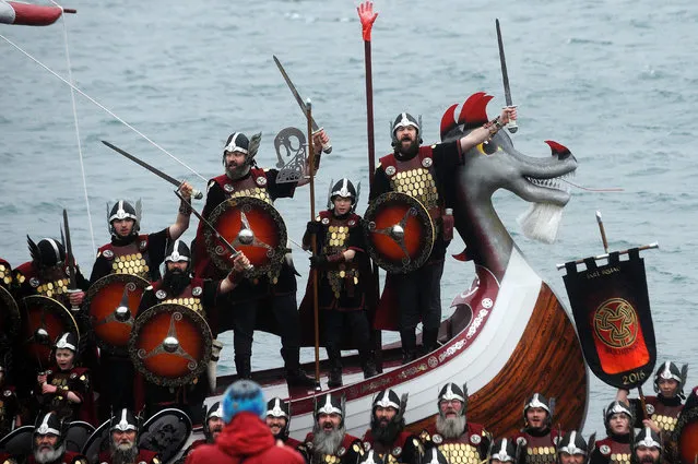 Participants dressed as Vikings stand in their long boat as they prepare to participate in the annual Up Helly Aa festival in Lerwick, Shetland Islands, on January 26, 2016. Up Helly Aa celebrates the influence of the Scandinavian Vikings in the Shetland Islands and culminates with up to 1,000 “guizers” (men in costume) throwing flaming torches into their Viking longboat and setting it alight later in the evening. (Photo by Andy Buchanan/AFP Photo)