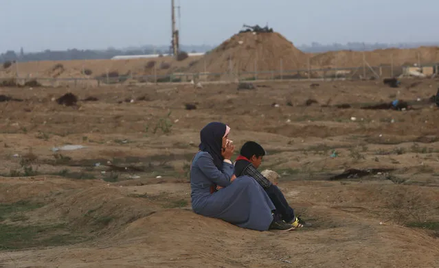 A protester and her child sit while inhaling teargas fired by Israeli troops near the fence of the Gaza Strip border with Israel during a protest east of Gaza City, Friday, November 9, 2018. Gaza's Hamas rulers said Friday that deadly protests along Gaza-Israel perimeter fence have achieved some goals; $15 million from Qatar to help pay the salaries of civil servants. (Photo by Adel Hana/AP Photo)