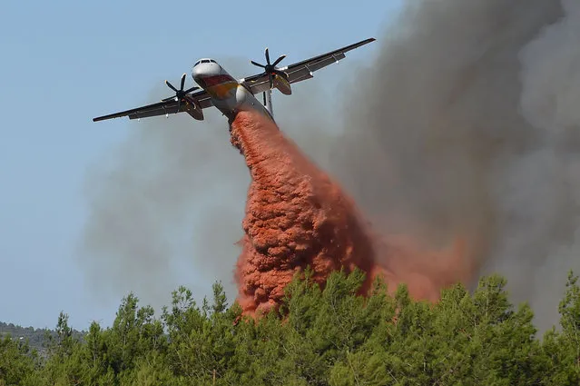 A Civil Security Bombardier Dash 8-Q400MR firefighting aircraft drops fire-retardant over a forest fire near Gignac, southern France, on July 26, 2022, as the country endures a dry summer with wildfires destroying numerous forests across France. (Photo by Sylvain Thomas/AFP Photo)