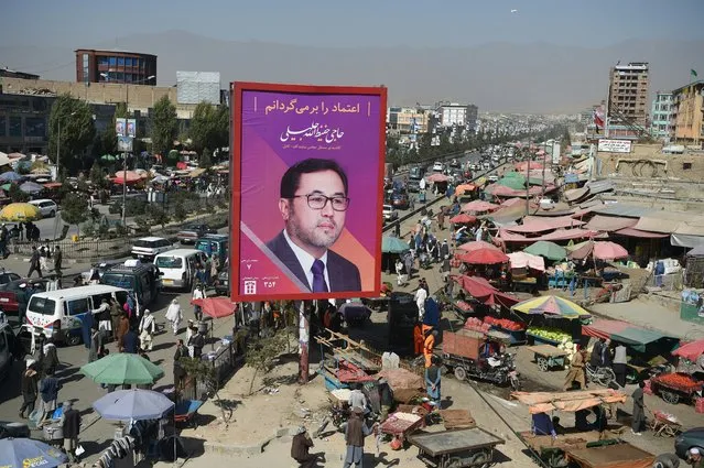 Afghan commuters and pedestrians are seen along road as a billboard with a poster of candidate Haji Hafizullah Jalili is seen near a busy market during the parliamentary election campaign, in Kabul on October 2, 2018. Campaigning for Afghanistan's long-delayed parliamentary elections kicks off on September 28, as a crescendo of deadly violence and claims of widespread fraud fuel debate over whether the vote will go ahead. (Photo by Wakil Kohsar/AFP Photo)