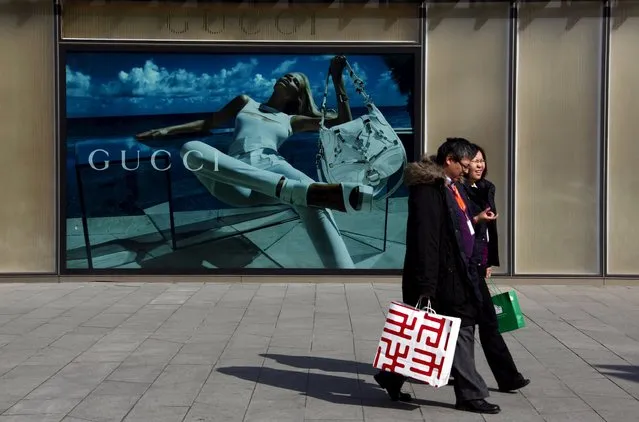 Shoppers walk past a billboard for fashion label Gucci in central Beijing in this December 7, 2010 file photo. More potential bad news for the global economic outlook: Chinese shoppers, who largely propped up growth last year, are likely to trim spending this year; dining out less often, delaying smartphone upgrades and cutting out impulse buys. (Photo by David Gray/Reuters)