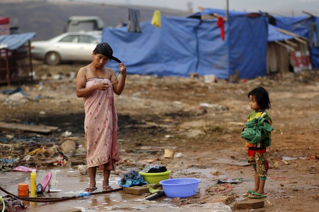 A girl watches her mother washing her hair at a refugee camp at Myanmar's border town with China, in Kokang March 24, 2015. (Photo by Wong Campion/Reuters)