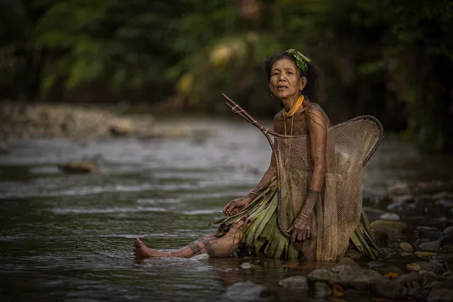Woman of the tribe wear traditional handmade skirts to catch fish in the local river taken on July 19, 2014 on the Mentawai Islands, Indonesia. (Photo by Muhamad Saleh Dollah/Barcroft Media)